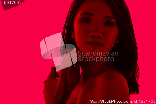 Image of High Fashion model woman in colorful bright lights posing in studio