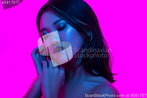 Image of High Fashion model woman in colorful bright lights posing in studio