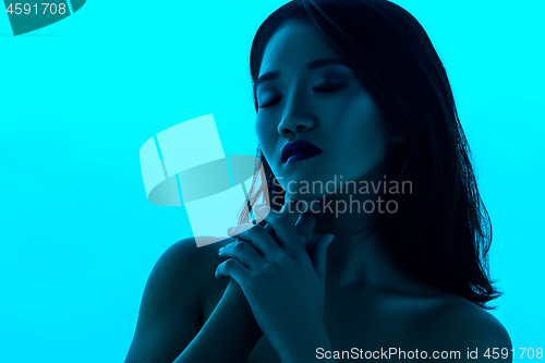 Image of High Fashion model woman in colorful bright lights posing in studio