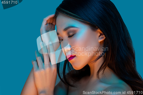 Image of High Fashion model woman in colorful bright lights posing in studio