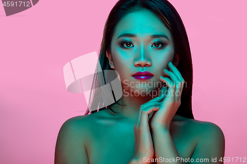 Image of High Fashion model woman in colorful bright lights posing in studio