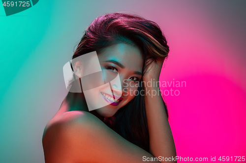 Image of High Fashion model woman in colorful bright lights posing in studio