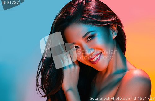 Image of High Fashion model woman in colorful bright lights posing in studio