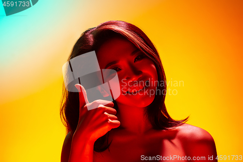 Image of High Fashion model woman in colorful bright lights posing in studio