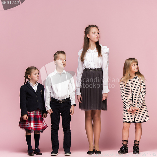 Image of Cute stylish children on pink studio background. The beautiful teen girls and boy standing together
