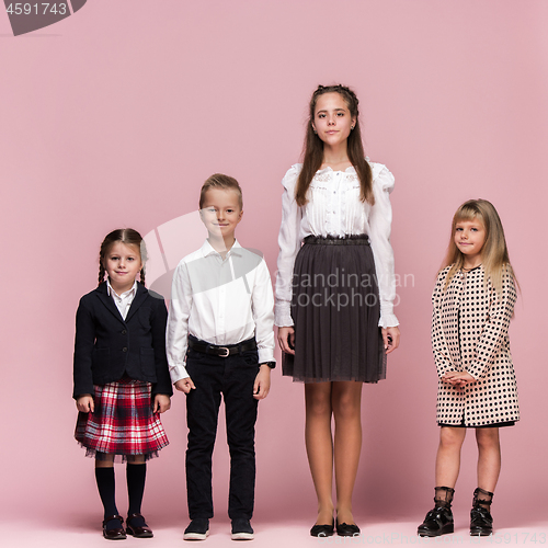 Image of Cute stylish children on pink studio background. The beautiful teen girls and boy standing together