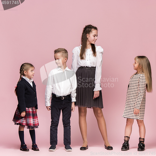 Image of Cute stylish children on pink studio background. The beautiful teen girls and boy standing together