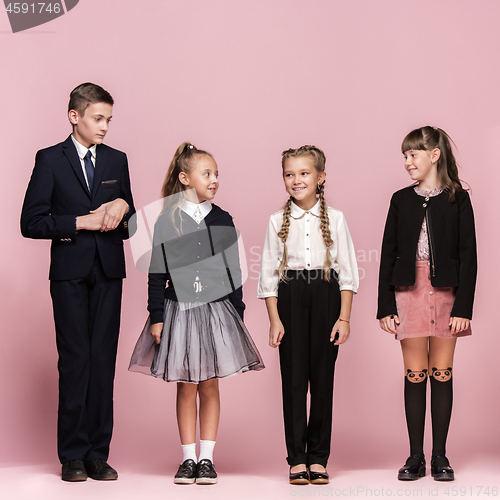 Image of Cute stylish children on pink studio background. The beautiful teen girls and boy standing together