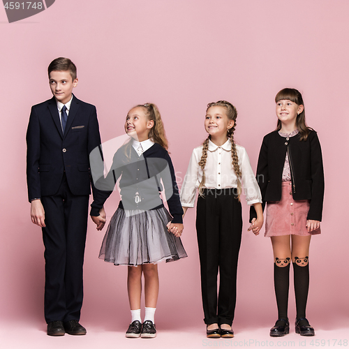Image of Cute stylish children on pink studio background. The beautiful teen girls and boy standing together
