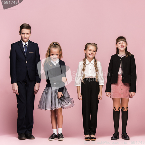 Image of Cute stylish children on pink studio background. The beautiful teen girls and boy standing together