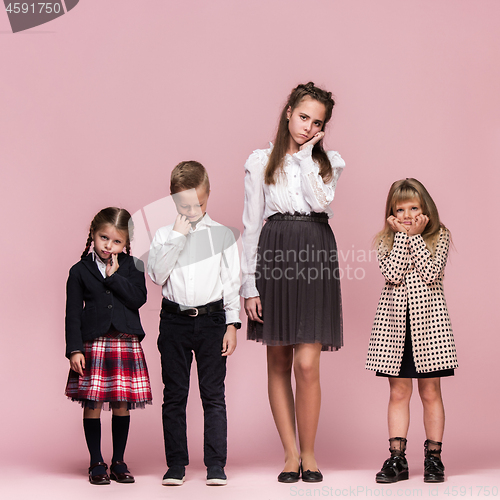 Image of Cute stylish children on pink studio background. The beautiful teen girls and boy standing together
