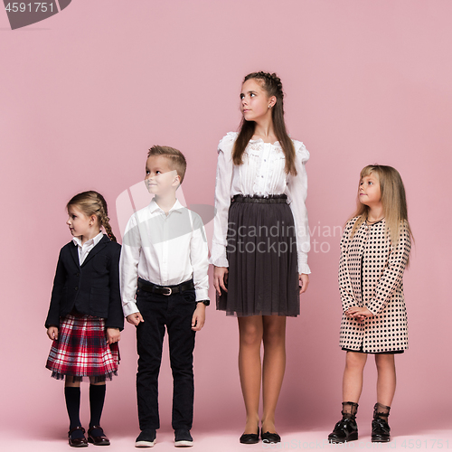 Image of Cute stylish children on pink studio background. The beautiful teen girls and boy standing together