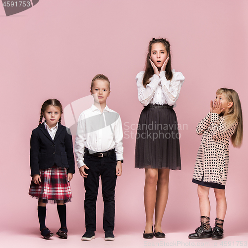 Image of Cute stylish children on pink studio background. The beautiful teen girls and boy standing together