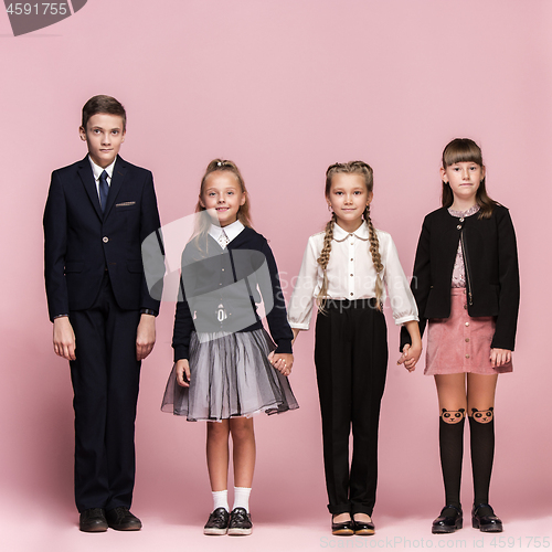 Image of Cute stylish children on pink studio background. The beautiful teen girls and boy standing together