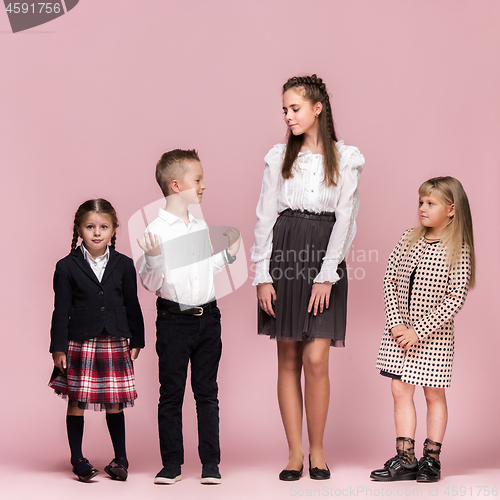 Image of Cute stylish children on pink studio background. The beautiful teen girls and boy standing together