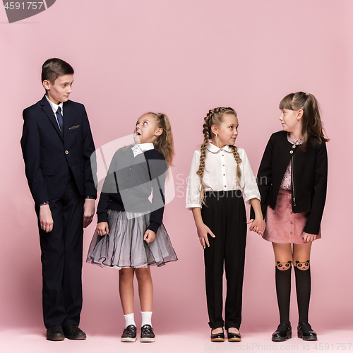 Image of Cute stylish children on pink studio background. The beautiful teen girls and boy standing together