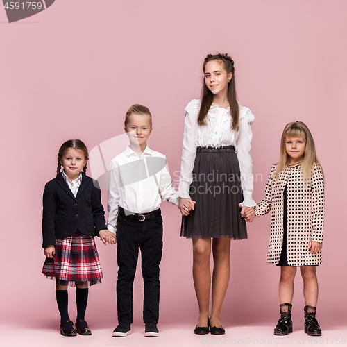 Image of Cute stylish children on pink studio background. The beautiful teen girls and boy standing together