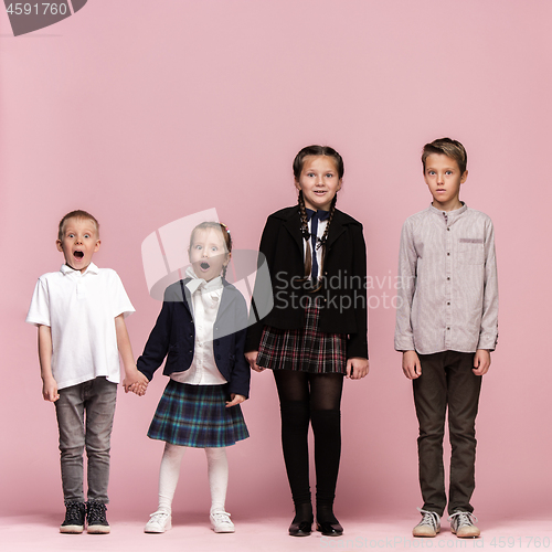 Image of Cute stylish children on pink studio background. The beautiful teen girls and boy standing together