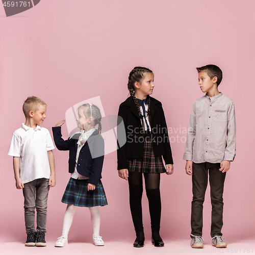 Image of Cute stylish children on pink studio background. The beautiful teen girls and boy standing together