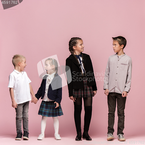 Image of Cute stylish children on pink studio background. The beautiful teen girls and boy standing together