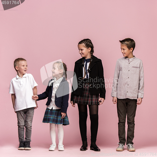 Image of Cute stylish children on pink studio background. The beautiful teen girls and boy standing together