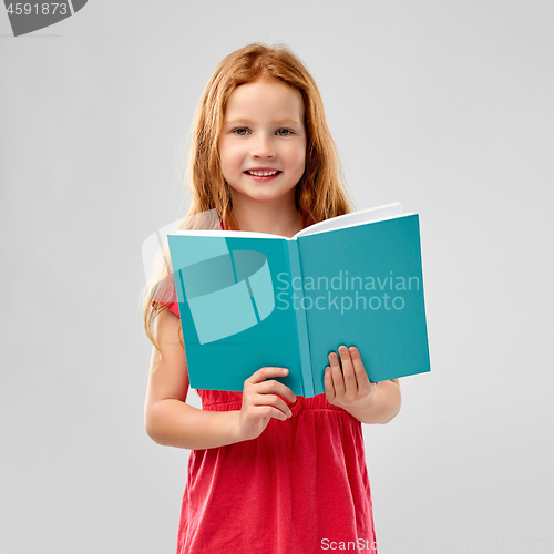 Image of smiling red haired girl reading book