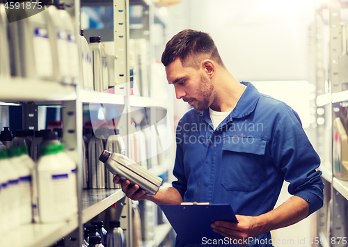 Image of auto mechanic with clipboard at car workshop