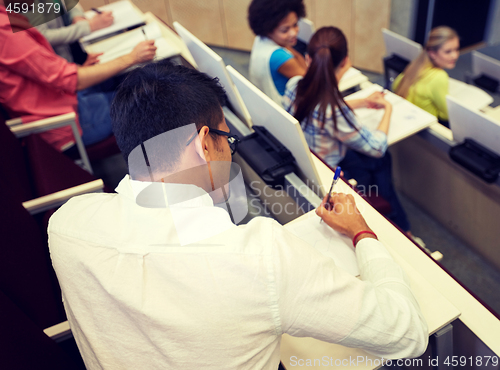 Image of group of students with notebooks in lecture hall