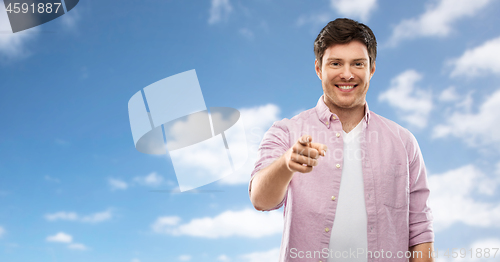Image of smiling man pointing fingers at you over sky