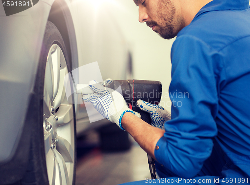 Image of mechanic with screwdriver changing car tire