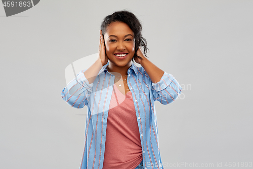 Image of happy african american woman closing ears by hands