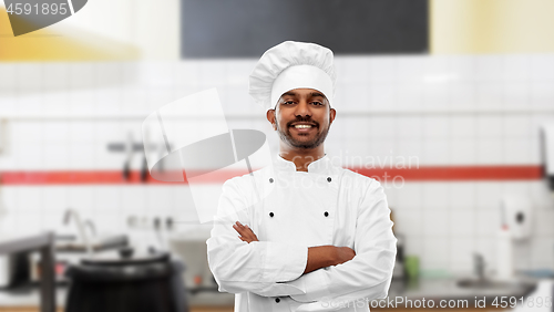 Image of happy indian chef in toque at restaurant kitchen