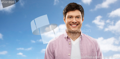 Image of smiling man over blue sky and clouds background