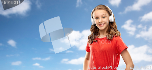 Image of happy teenage girl in headphones over sky