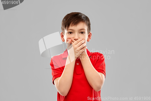 Image of shocked boy in red t-shirt closing mouth by hands