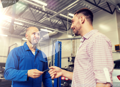 Image of auto mechanic giving key to man at car shop