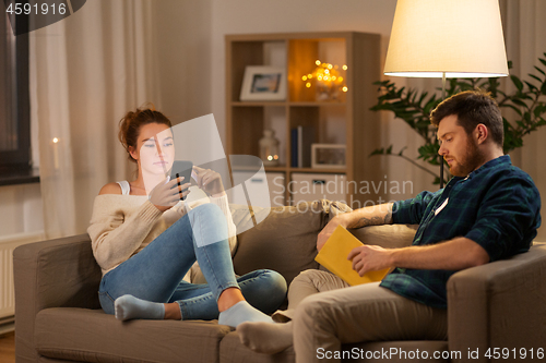 Image of couple with smartphone and book at home