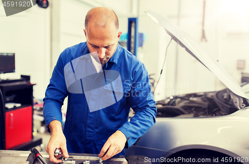 Image of mechanic man with wrench repairing car at workshop