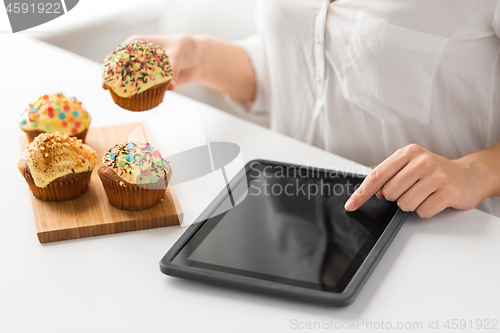 Image of close up of woman with tablet pc and cupcake