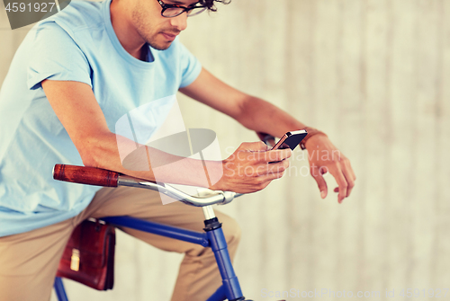 Image of man with smartphone and fixed gear bike on street