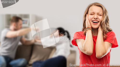 Image of girl covering ears over her parents having fight