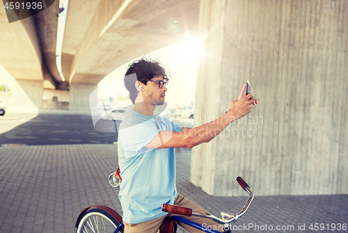 Image of man with smartphone and earphones on bicycle