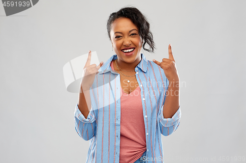 Image of happy african american woman making rock gesture