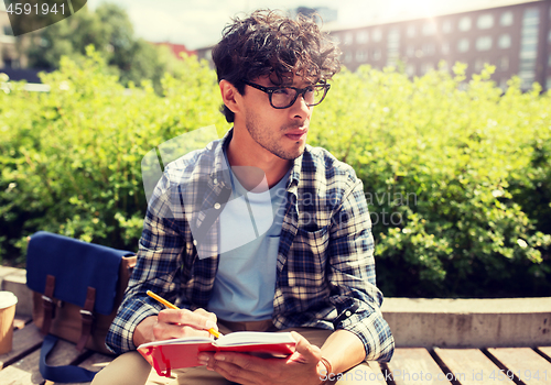 Image of man with notebook or diary writing on city street