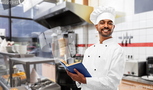 Image of happy indian chef with cookbook at kebab shop