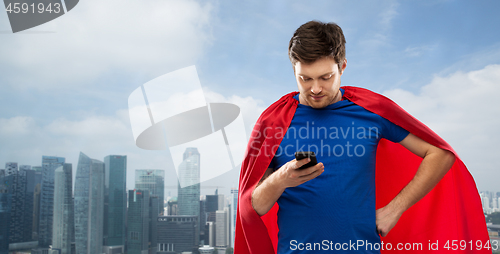 Image of man in superhero cape using smartphone over city