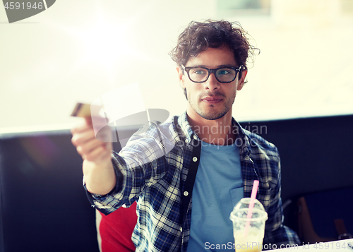 Image of happy man paying with credit card at cafe