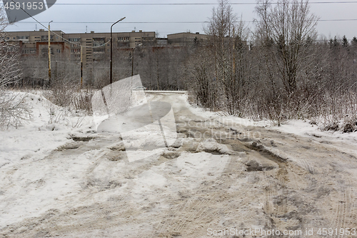 Image of Bad road with deep holes, water, ice and snow in Russian city in winter