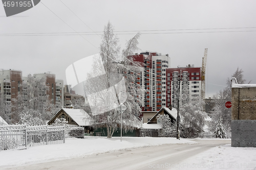 Image of Old wooden houses on background of new tall city houses in winter