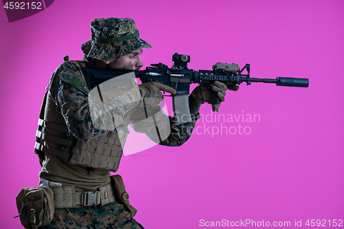 Image of soldier in action aiming laseer sight optics pink background